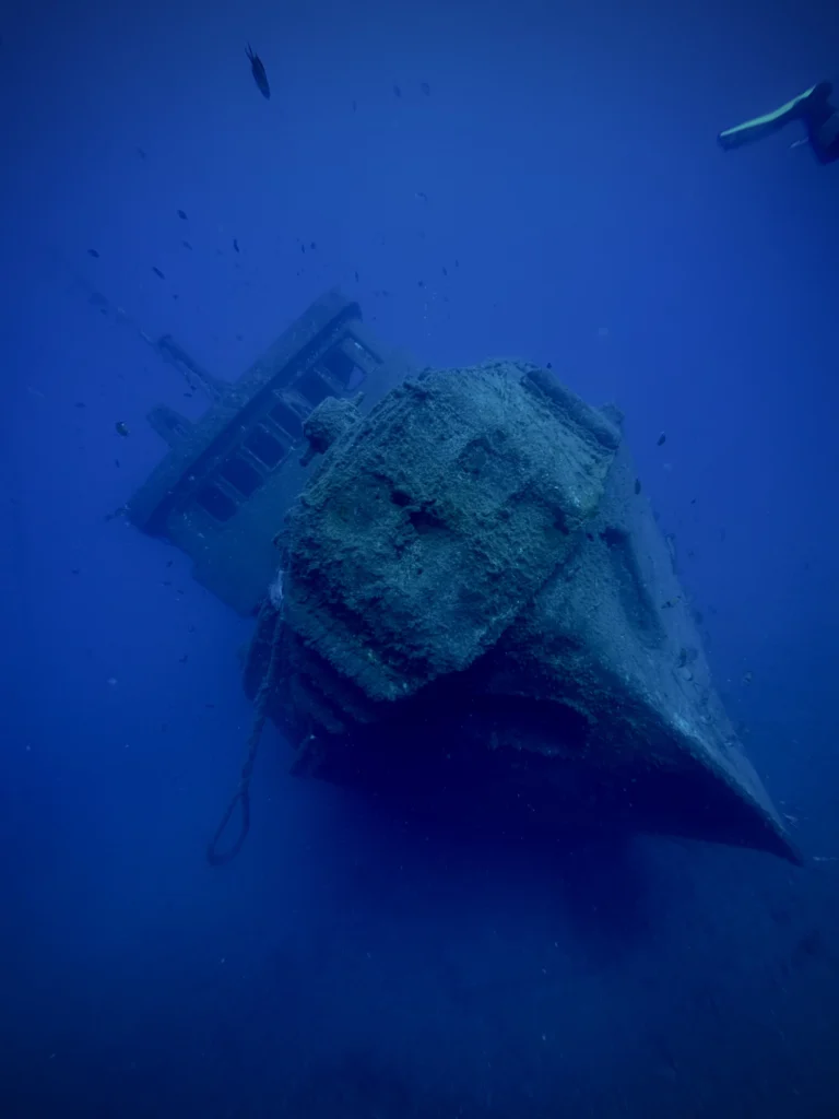 Divers exploring the El Peñón wreck in Tenerife, a popular wreck diving site surrounded by schools of fish and volcanic reef.