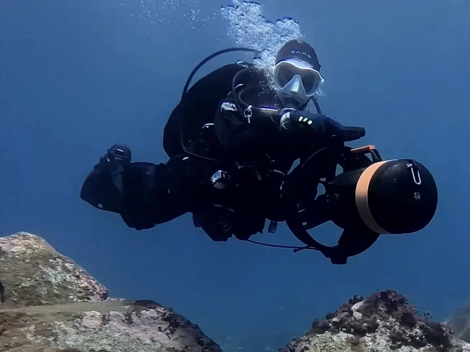 Diver using underwater scooter DPV over volcanic rock formations in Tenerife on the SSI Scooter Specialty course at Barbarian Diving