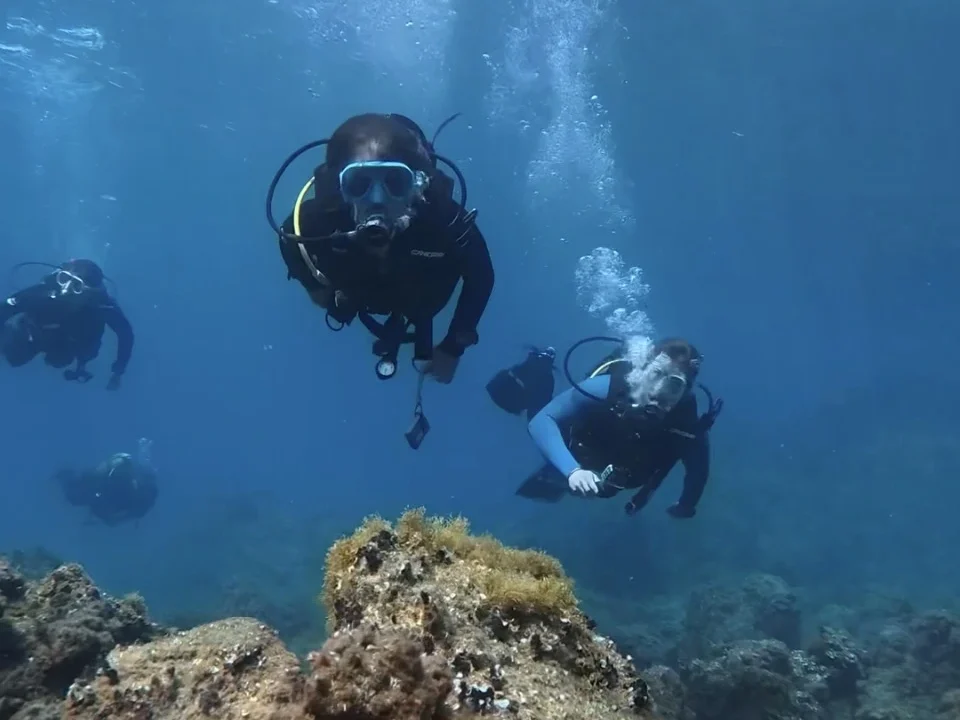 SSI Scuba Diver course students diving over volcanic reef in Tenerife with Barbarian Diving instructor