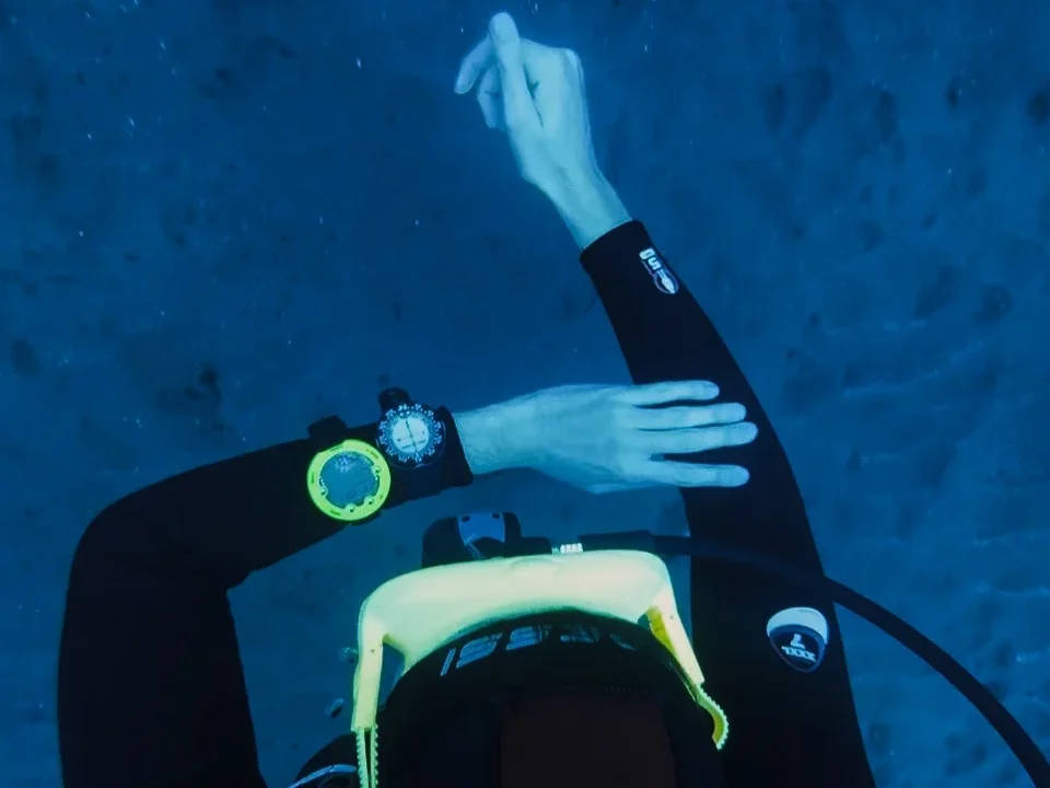 SSI Navigation specialty course diver underwater in Tenerife, using wrist compass and pointing direction during training dive with Barbarian Diving, Canary Islands.
